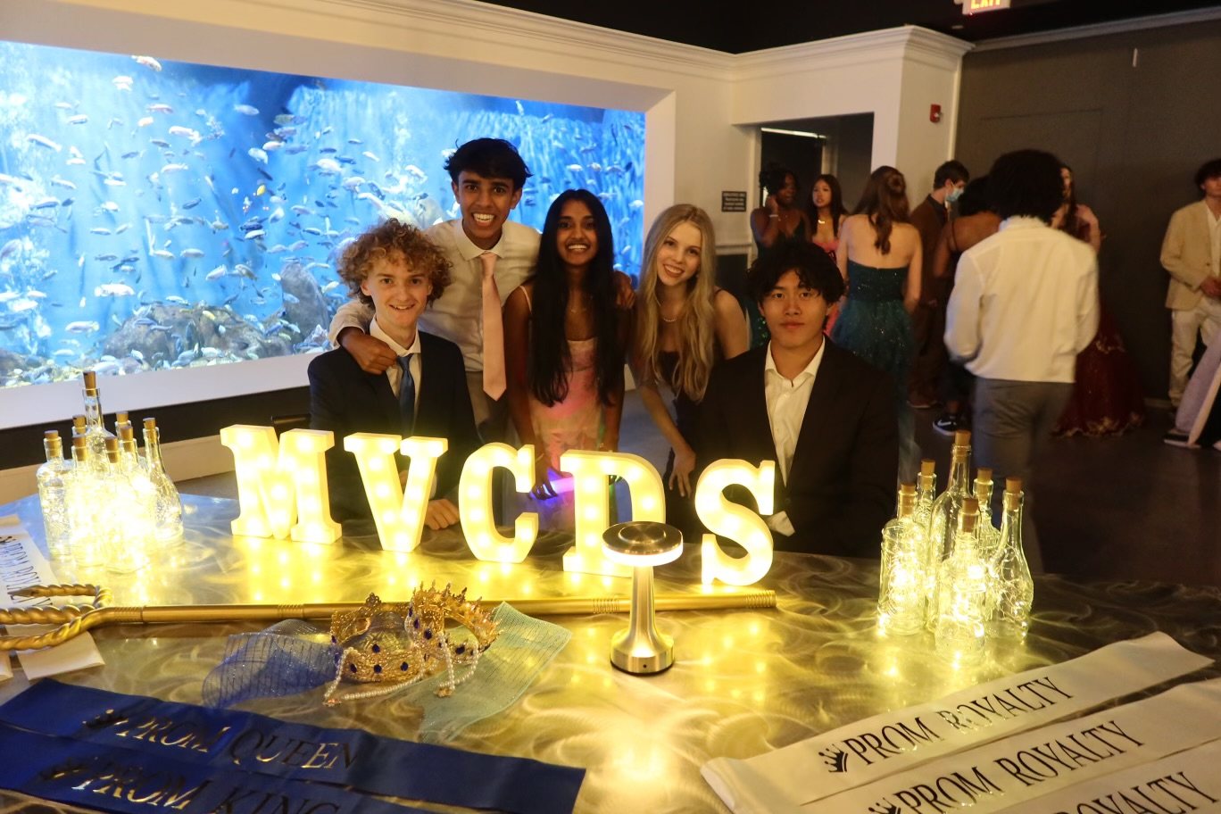 Students at a school dance in front of illuminated MVCDS letters.