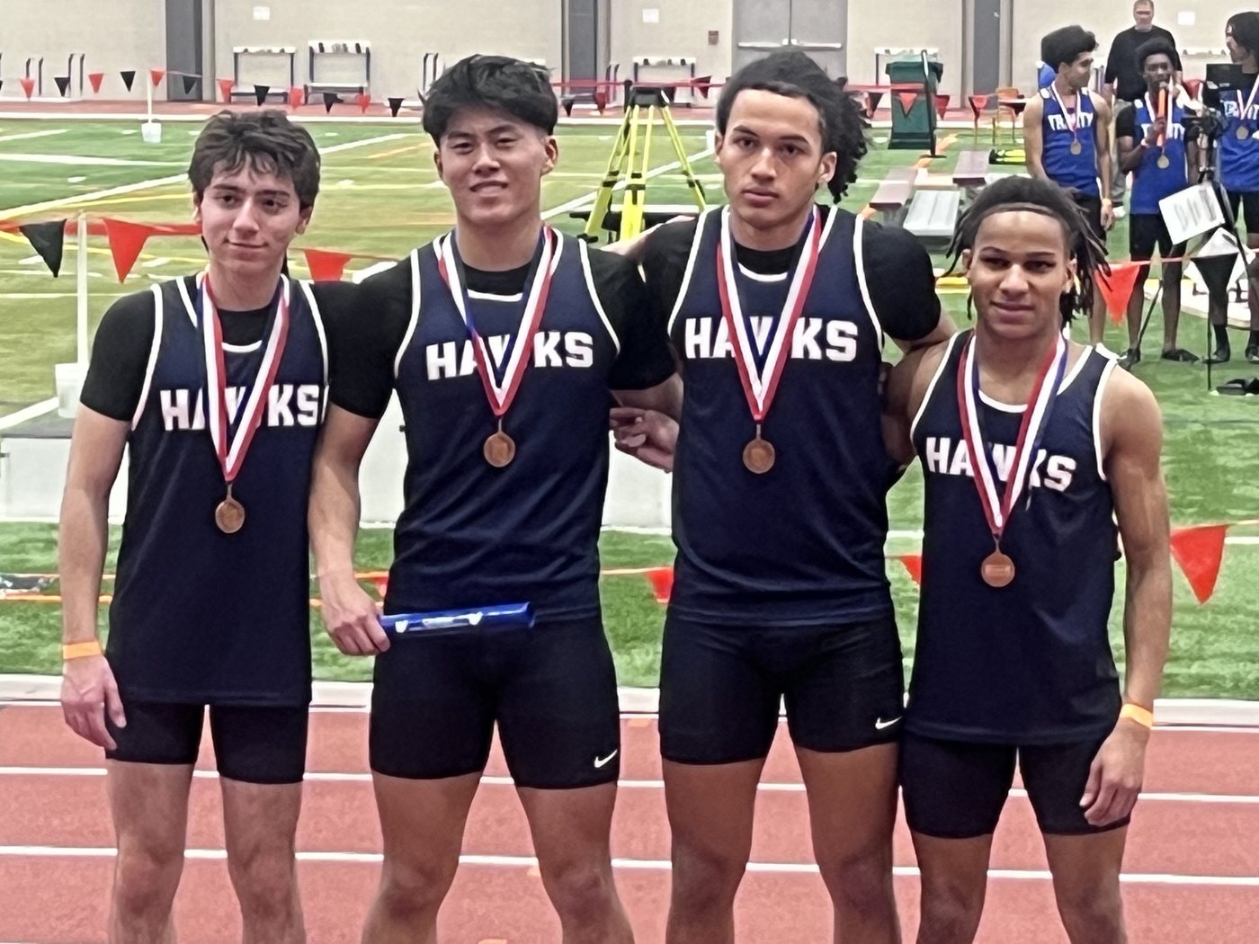 Four Hawks track athletes standing together on the track with medals.