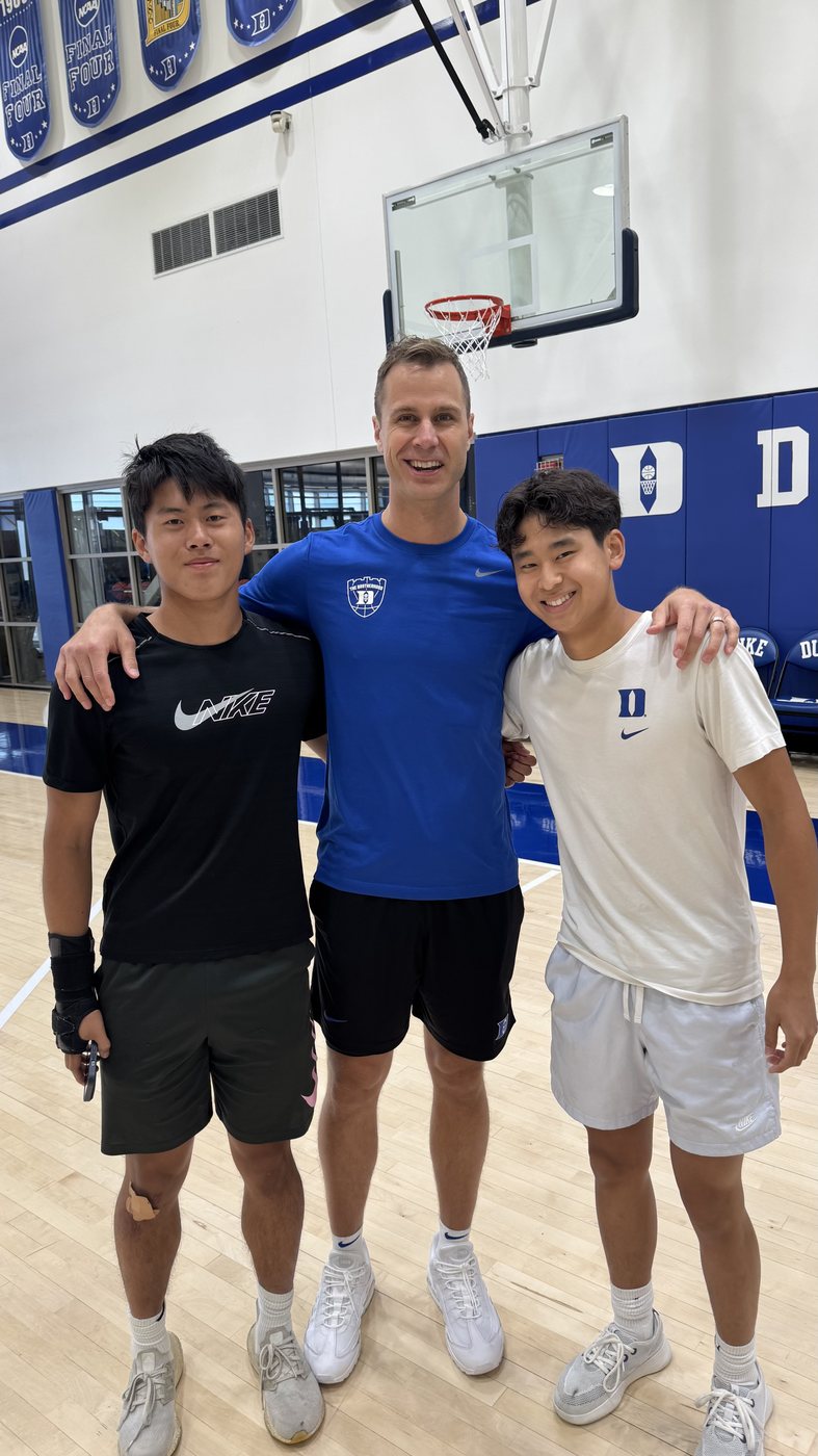 Joshua Wang and two others standing on a Duke basketball court under the hoop.