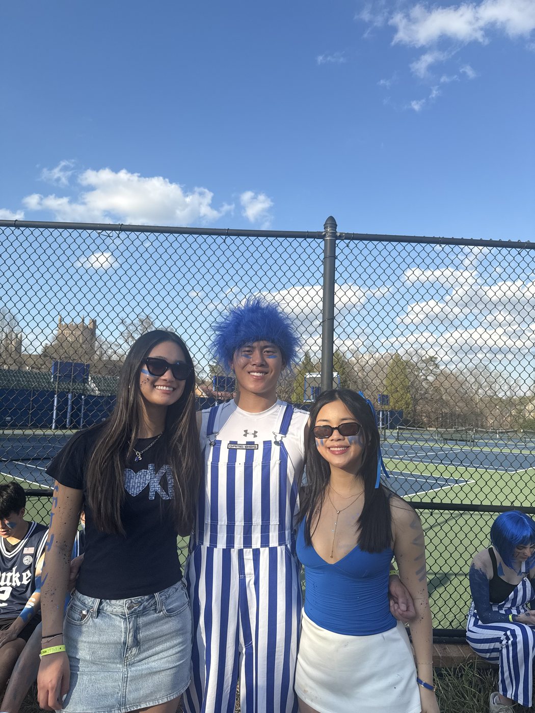 Joshua Wang with two friends at an outdoor Duke sporting event.