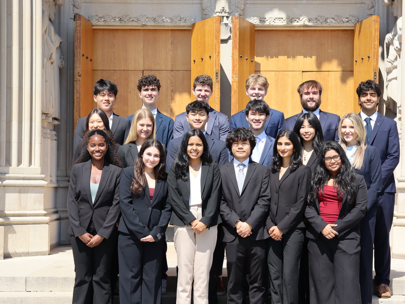 A group of students in business attire posing on chapel steps.