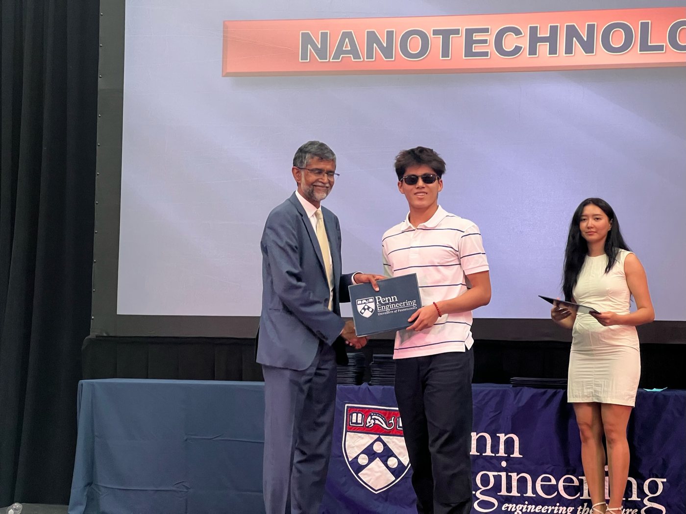 Joshua Wang receiving a certificate on stage at a Penn Engineering nanotechnology program ceremony.